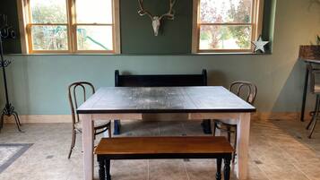A dining area with a wooden table, chairs, a bench, and a wall-mounted deer skull.