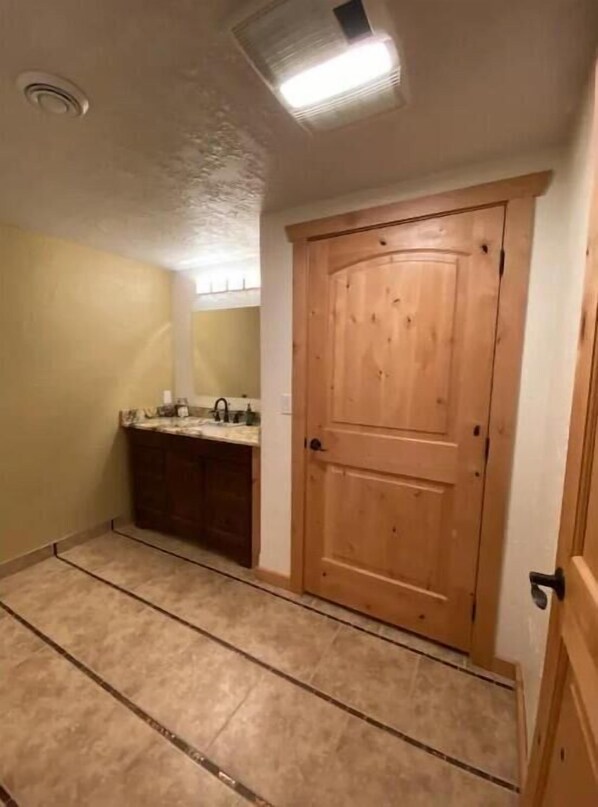 A bathroom with a wooden door, a sink, and a mirror.