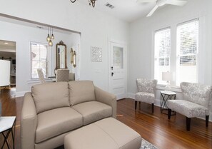 A spacious living room with a beige sofa, patterned armchairs, and a small side table.