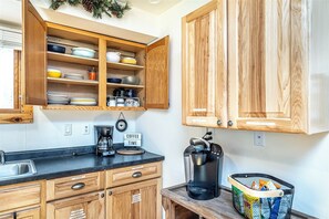 A kitchen with wooden cabinets, a coffee maker, and a trash can. - Cozy Ski Retreat on UTV/Snowmobile Trail (Merrillan)
