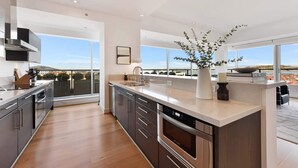 A modern kitchen with a large island, stainless steel appliances, and a view of the city.