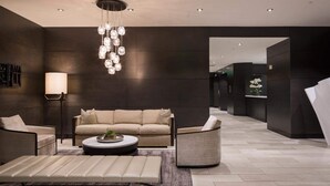 A modern living room with a sofa, armchairs, a coffee table, and a hanging light fixture.