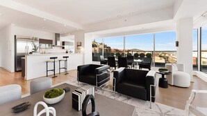 A modern apartment with a kitchen, dining area, and a balcony with a city view.
