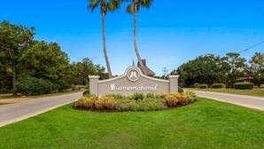 A sign with the name 'Diamondhead' surrounded by well-maintained grass and palm trees. - 1st Floor 1BR/1BA Condo w/ Pool: Golf, Swim & Casino nearby! Sunshine Oaks (Diamondhead)