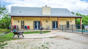 Een gebouw met twee verdiepingen, een overdekte patio, zitplaatsen buiten en een barbecue.