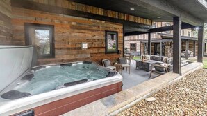 A hot tub area with wooden paneling, outdoor seating, and a stone pathway. - Whitefish Lynx Run Town House Private Hot Tub (Whitefish)