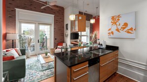 A modern kitchen with a large island, wooden cabinets, and pendant lights. - Cozy Condo Front Street Wilmington Private Balcony Walking distance  (Wilmington)