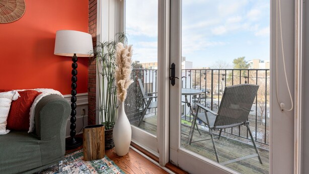 A balcony with a wicker chair, a potted plant, and a view of the cityscape. - Cozy Condo Front Street Wilmington Private Balcony Walking distance  (Wilmington)