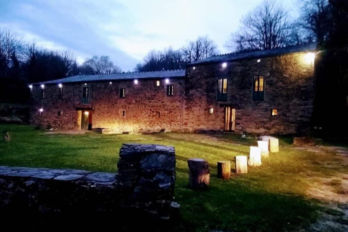 A stone building with multiple windows and a well-lit entrance.