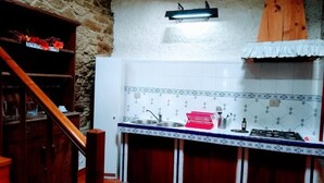A kitchen with a wooden staircase, a tiled backsplash, and a gas stove. - Casa Pacios By M De Santiago (Triacastela)