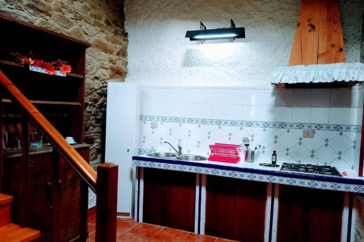 A kitchen with a wooden staircase, a tiled backsplash, and a gas stove.