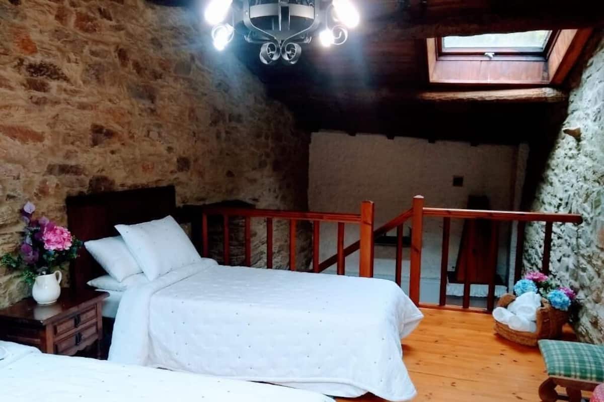 A rustic bedroom with a wooden bed, a small table with flowers, and a wooden railing.