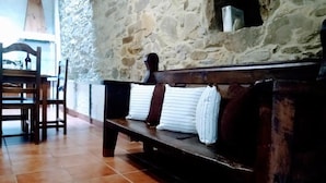 A rustic interior with a stone wall, wooden bench, and tiled floor. - Casa Pacios By M De Santiago (Triacastela)