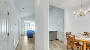 Un interior moderno con una zona de comedor que presenta una mesa y sillas de madera, un sofá azul y un sofá gris.