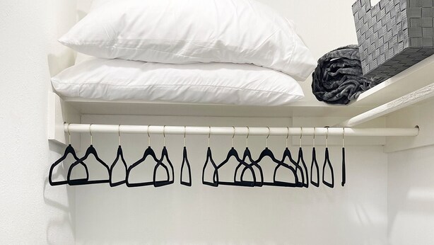 A laundry area with a hanging rack, a black laundry basket, and stacked white pillows. - Pet-friendly 4-bedroom PLUS Office and Hot Tub (Dallas)