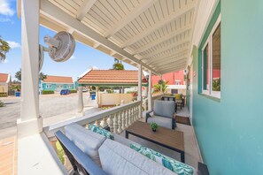 A covered outdoor seating area with a fan, a table, and a bench.