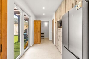 Eine Küche mit Kühlschrank, Holzschränken und einer Schiebetür zu einer Terrasse.