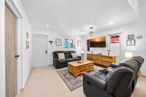 Un salon moderne avec un canapé, une table basse et un téléviseur fixé au mur.