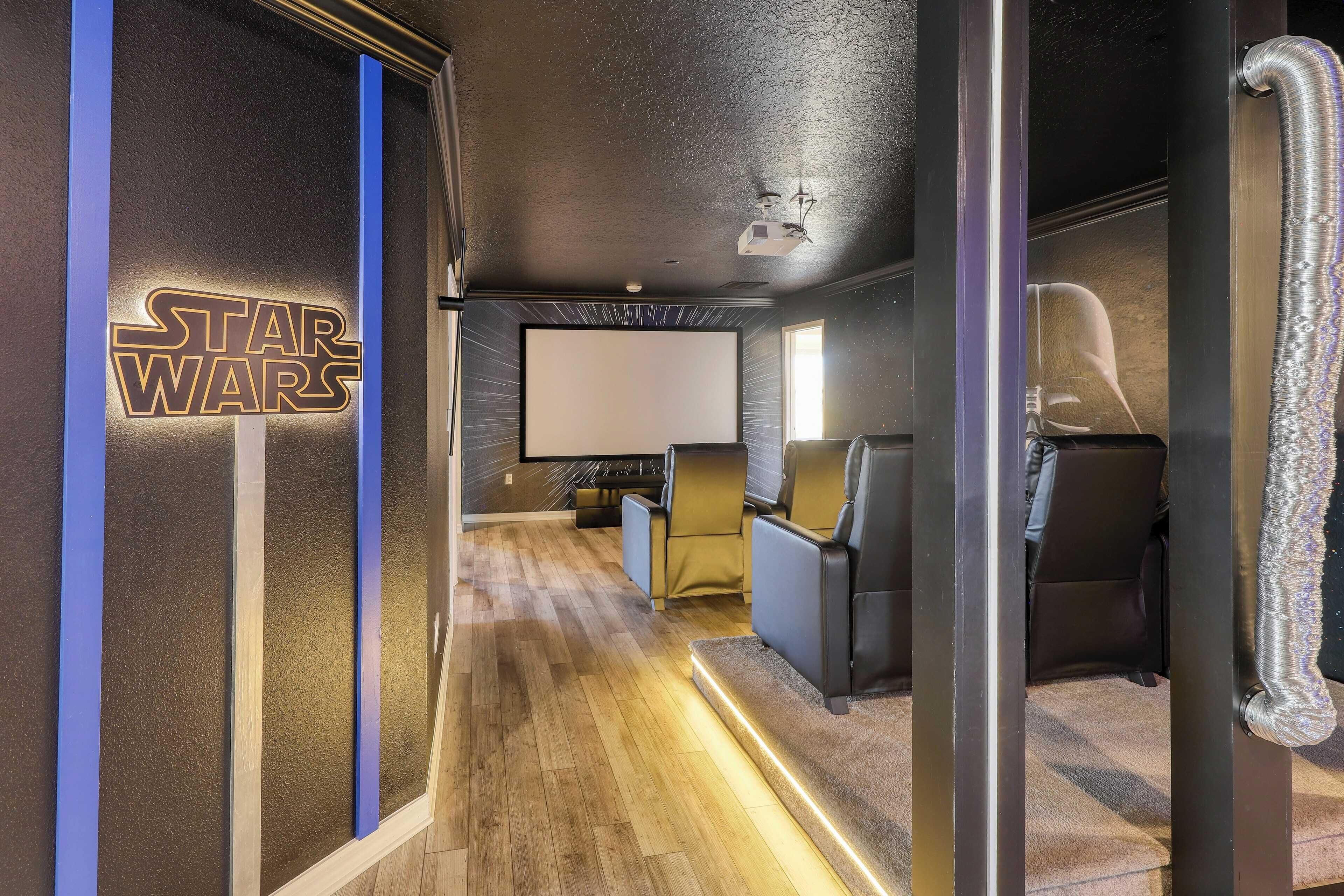 Una habitación temática de Star Wars con una pantalla grande, asientos cómodos y un proyector.