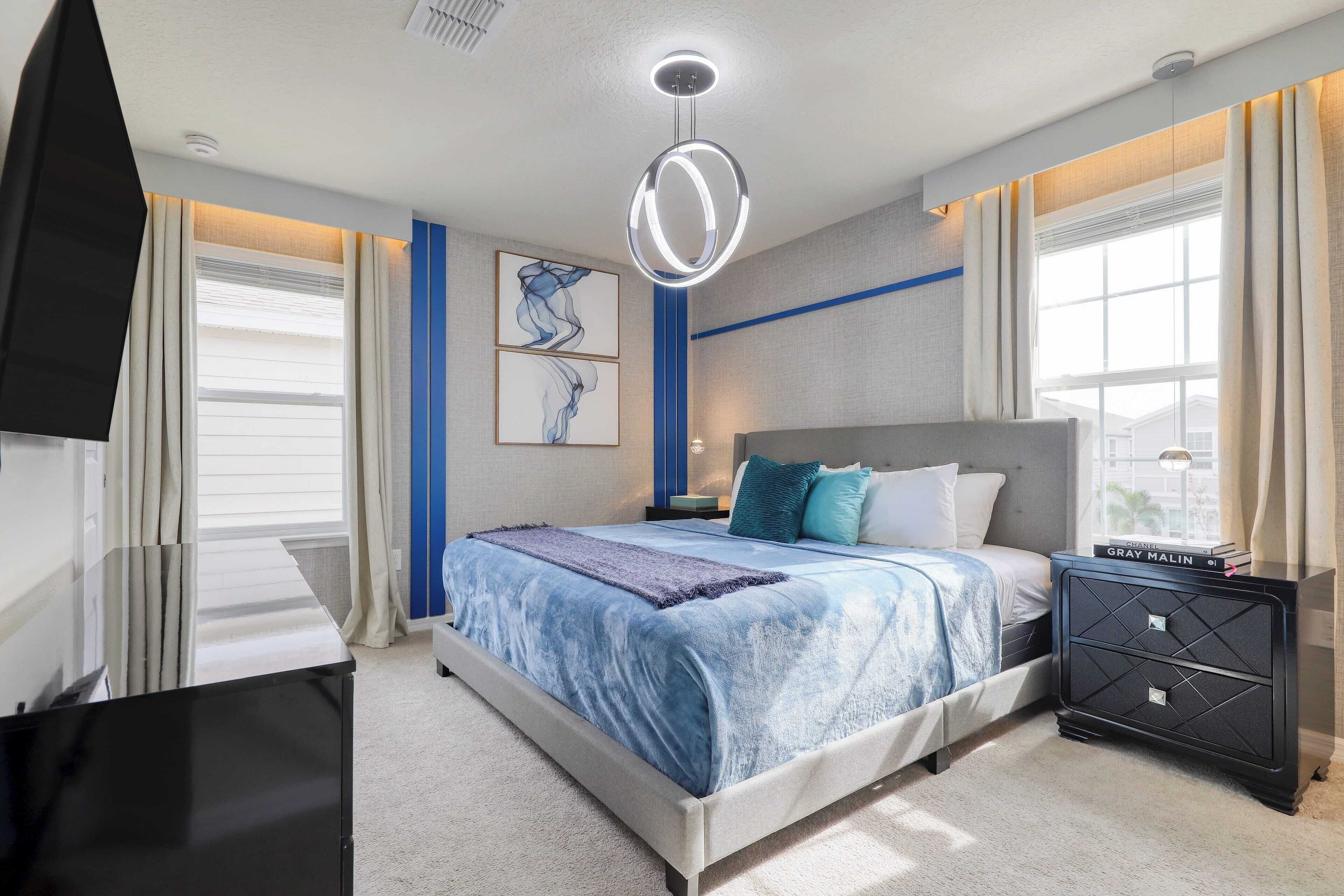 Une chambre à coucher moderne avec un grand lit, une table de chevet avec un livre et une commode.