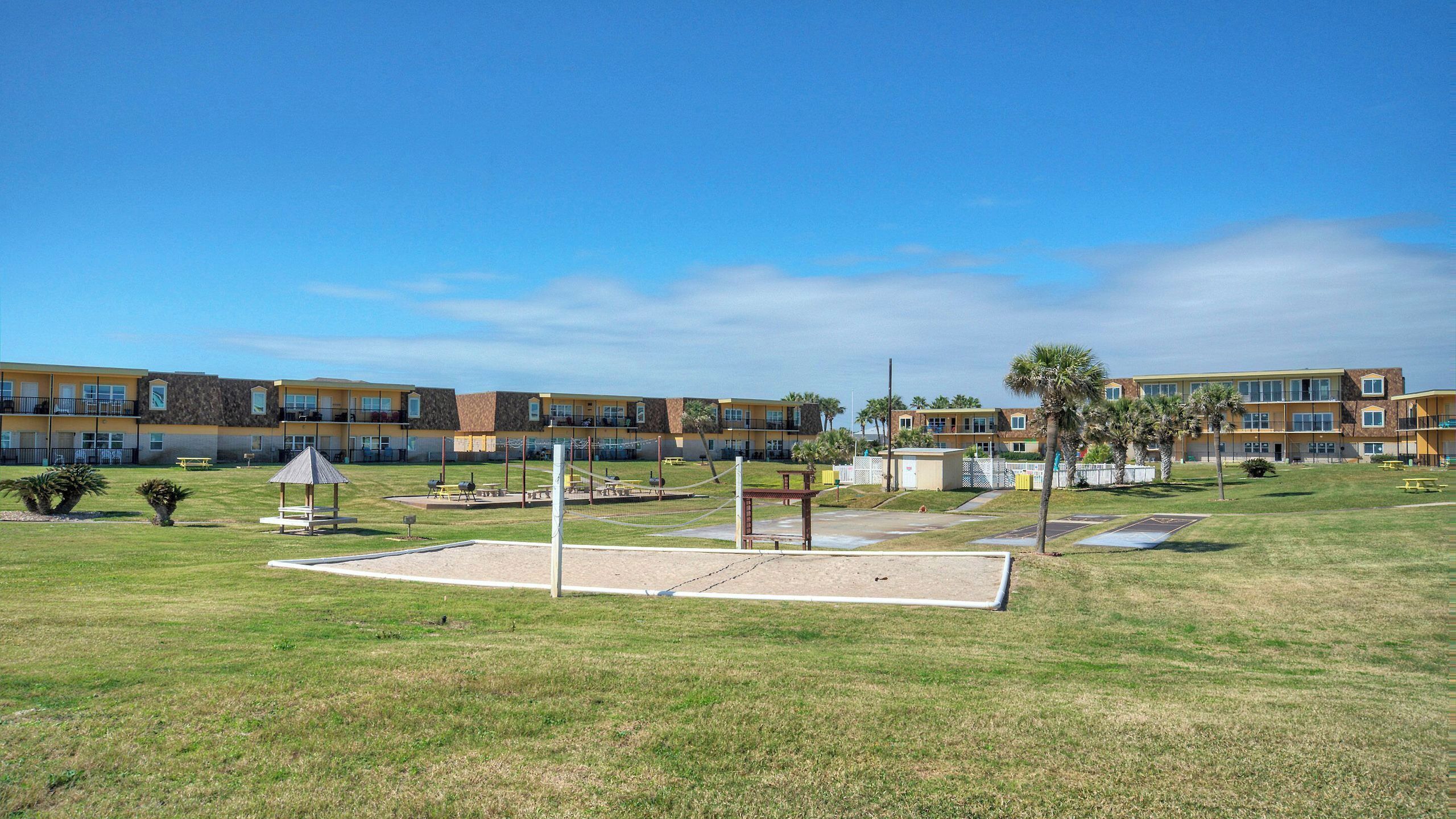 A courtyard with a volleyball net, picnic tables, and a playground.