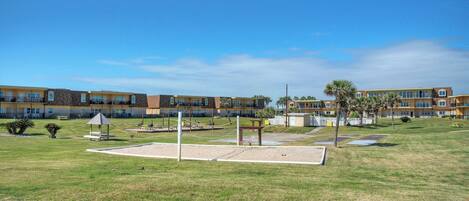 A courtyard with a volleyball net, picnic tables, and a playground.