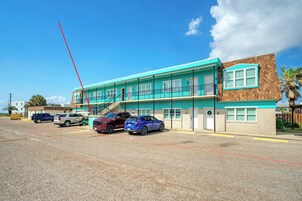 Un bâtiment à deux étages, doté d’une façade turquoise et d’une partie en briques brunes. Plusieurs voitures sont garées devant.