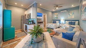 A compact living space with a kitchenette, two beds, and a ceiling fan. - 2 Pools, Beach Boardwalk Access Studio, Sleeps 5 Beach Bungalow by Avantstay (Port Aransas)