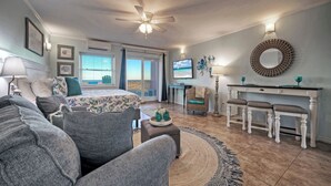 Un salon comprenant un lit, un canapé, un coin repas avec une table et des chaises, un téléviseur et un ventilateur de plafond.