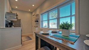 Eine moderne Küche mit Holztischplatte, zwei weißen Schüsseln, einem Blumentopf und einem Fenster mit Jalousien.