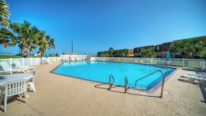 Una piscina con sillas de descanso y una cerca blanca.