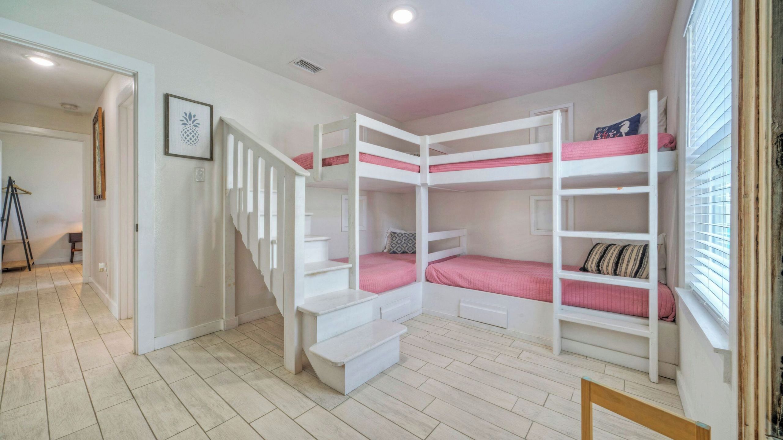 Ein Zimmer mit Etagenbetten, einer Treppe und einer Tür zu einem weiteren Raum.