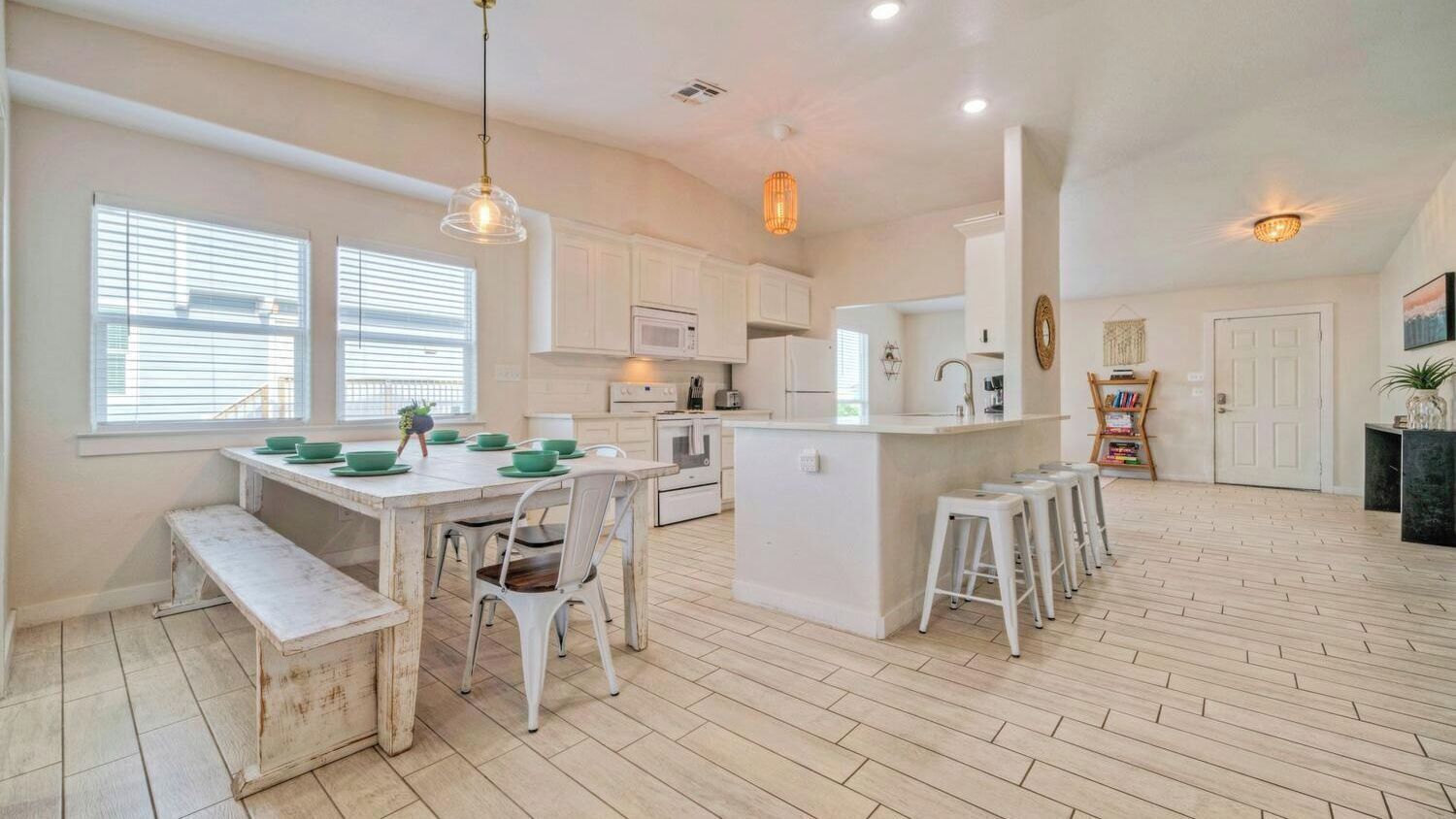 A spacious kitchen with white cabinetry, a central island, and bar stools.