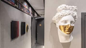 A hallway with a bookshelf, framed artwork, and a bust sculpture.