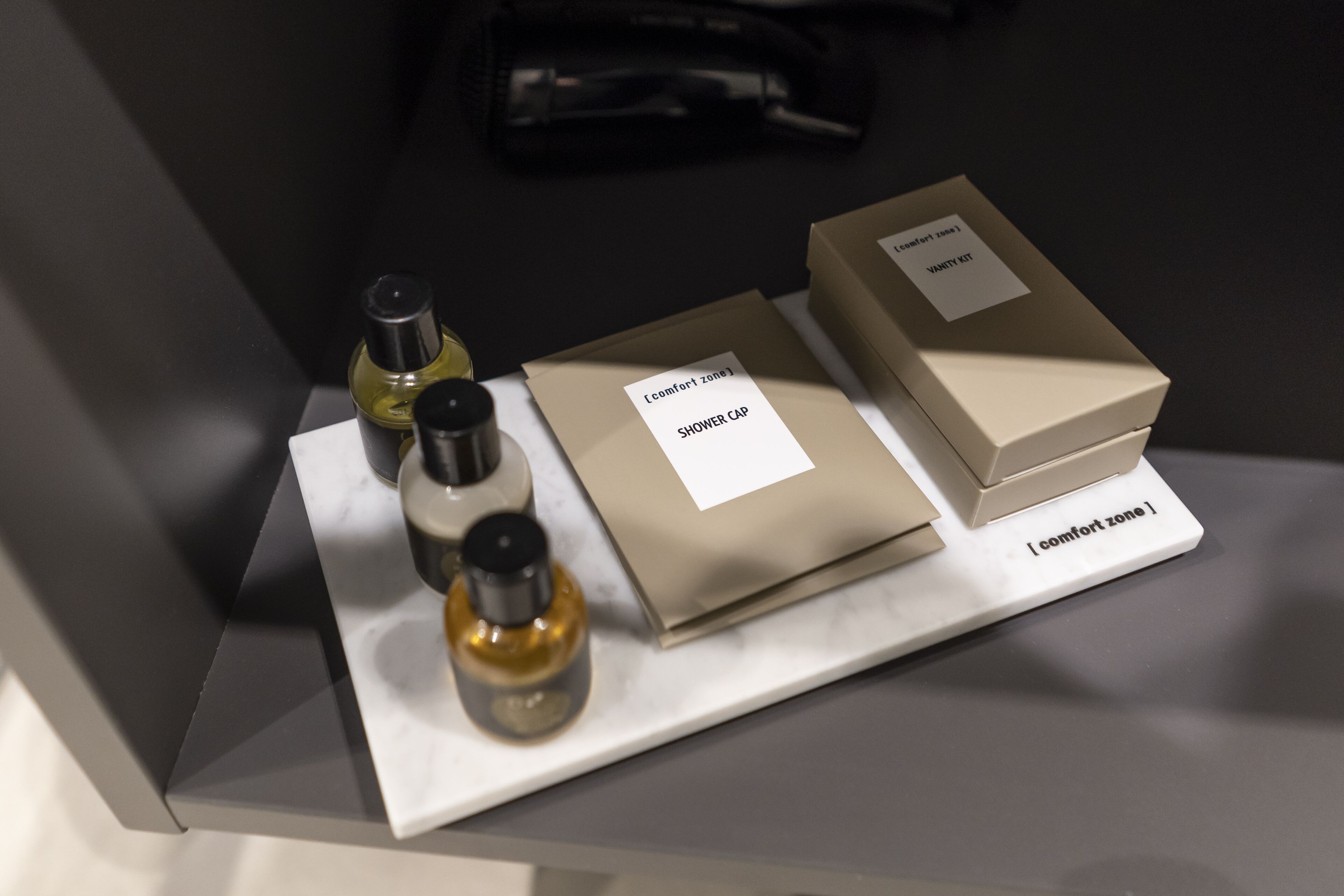 A display of toiletries including a shower cap, a bottle of liquid, and a box labeled "Comfort Zone."