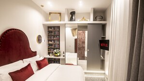 A hotel room with a large bed, a bookshelf, a TV, and a bathroom visible through an open door. - Three Rooms Toledo Luxury (Naples)
