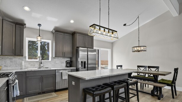 A modern kitchen with dark cabinets, stainless steel appliances, and a central island with bar stools.