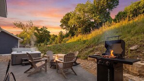 Un patio exterior con jacuzzi, mobiliario y una parrilla.