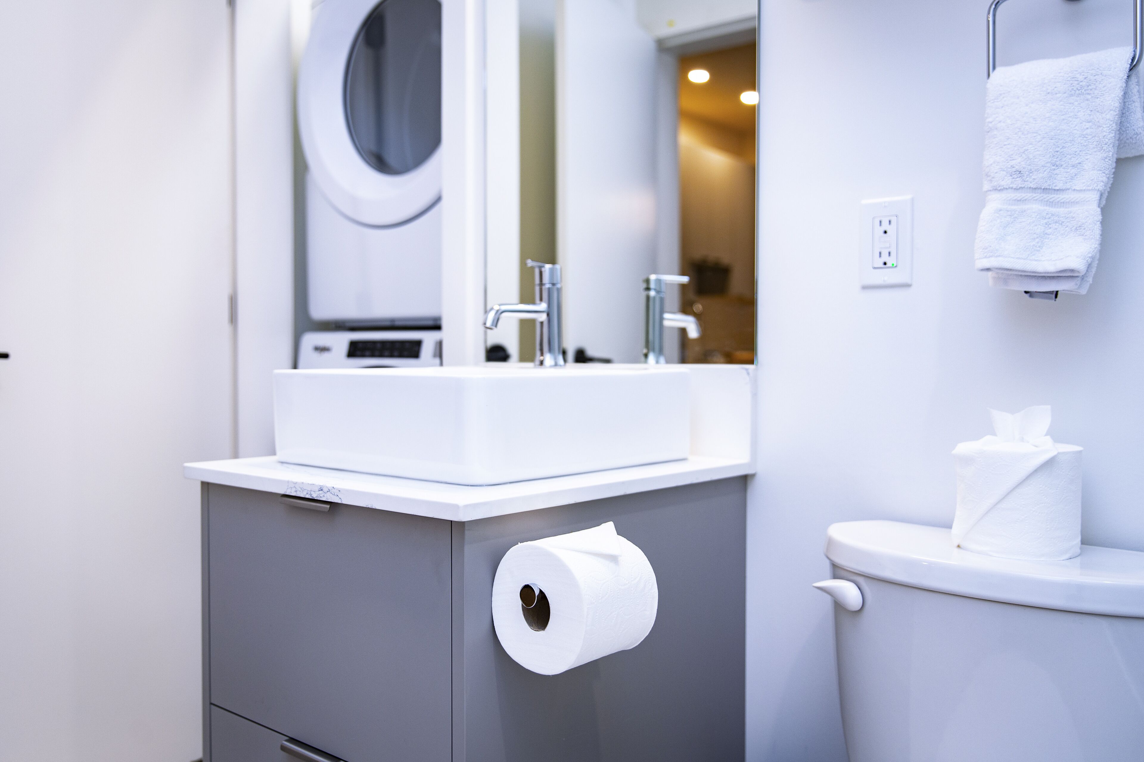 A bathroom with a white sink, a toilet, and a paper towel dispenser.