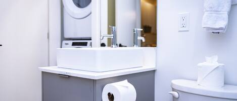 A bathroom with a white sink, a toilet, and a paper towel dispenser.