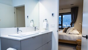 Une salle de bain moderne avec deux vasques, un grand miroir et un porte-rouleau de papier toilette.
