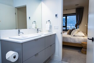 Un baño moderno con lavamanos dobles, un espejo grande y un rollo de papel higiénico.