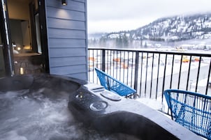 Un jacuzzi en un balcón con vistas a un paisaje nevado y montañas.