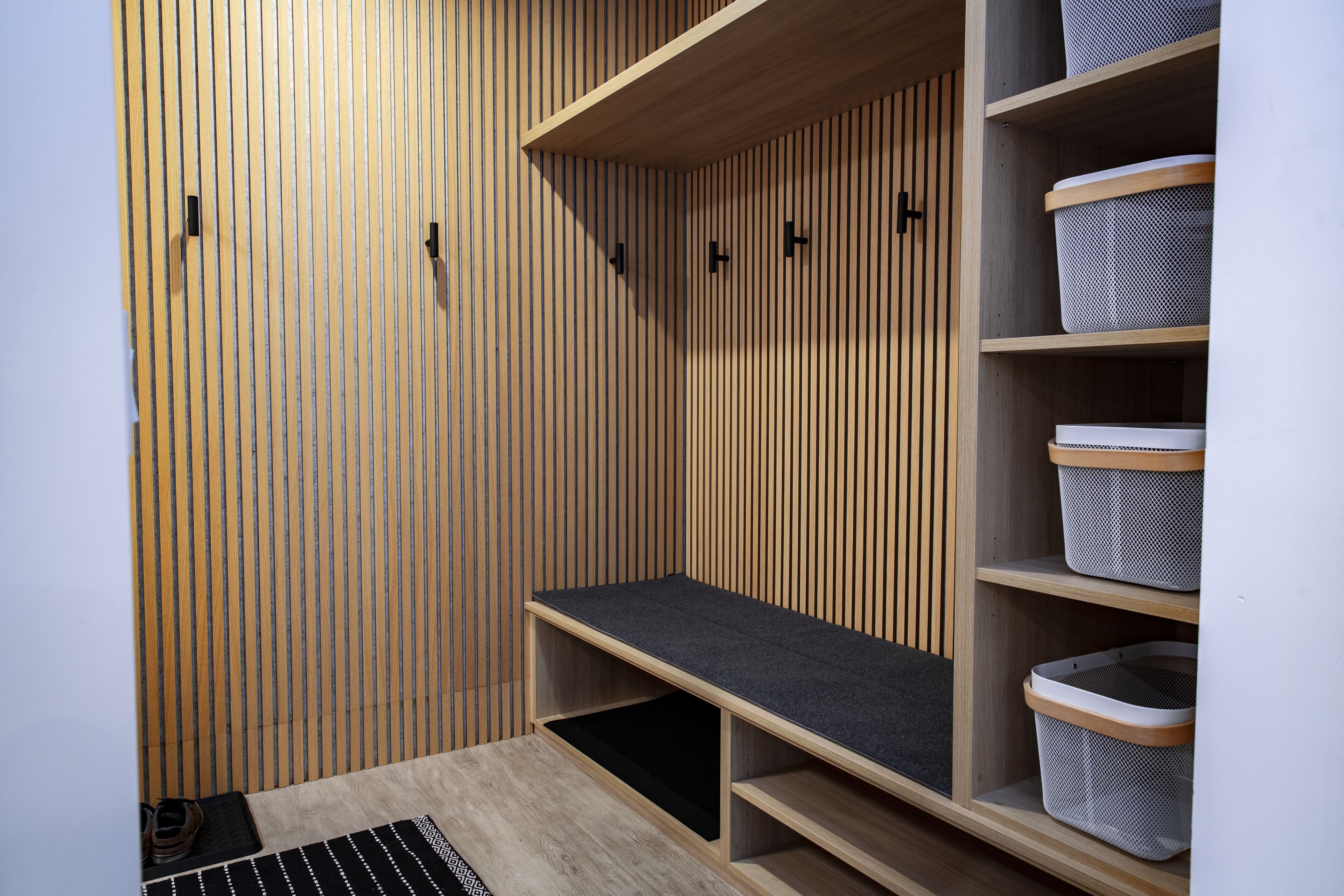 A storage closet with wooden slat walls, shelves, and baskets.