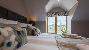 Een slaapkamer met een groot bed, een dakraam en uitzicht op de omgeving.