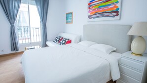 A modern hotel room with a large bed, a bedside table with a lamp, a view of the balcony, and a colorful abstract painting on the wall. - nalon inn (Madrid)