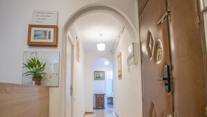 A hallway with a wooden reception desk, a potted plant, framed pictures, and a brown door with a lock. - nalon inn (Madrid)