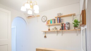 A room with a wooden reception desk, a wall-mounted clock, and shelves with books and a potted plant. - nalon inn (Madrid)
