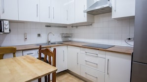 A modern kitchen with white cabinets, a wooden countertop, and a stainless steel sink. - nalon inn (Madrid)