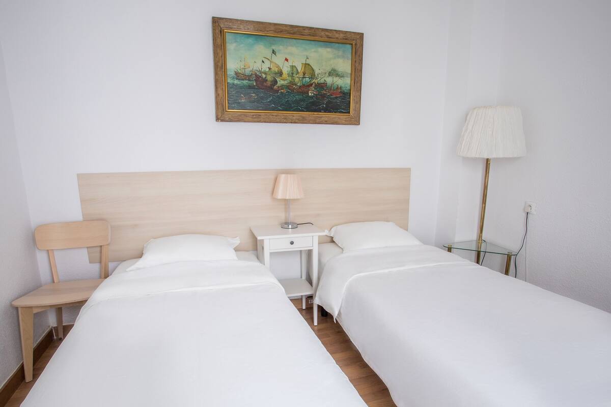 Une chambre d’hôtel avec deux lits, une table de chevet, une lampe et un tableau au mur.